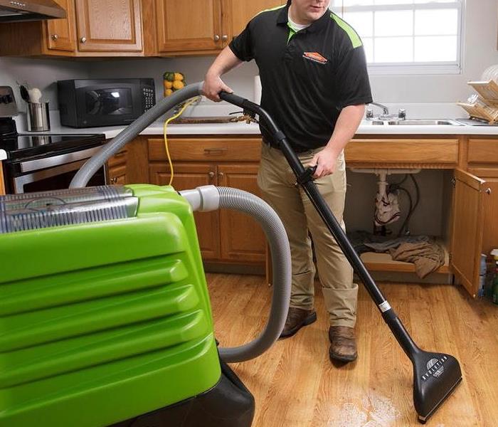 SERVPRO employee cleaning up a Kitchen that has over flown with water..